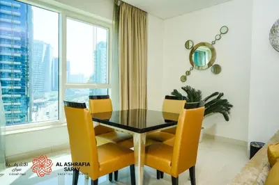 a dining room with a glass table and yellow chairs at Alashrafia Saray - Fabulous 1BR in Canal Views in Dubai