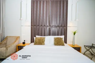 a bedroom with a large bed and a chair at Alashrafia Saray - Fabulous 1BR in Canal Views in Dubai