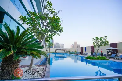 a large swimming pool with a palm tree next to a building at Alashrafia Saray - Fabulous 1BR in Canal Views in Dubai
