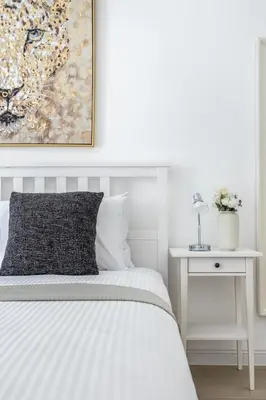 a white bedroom with a bed and a painting on the wall at Frank Porter - Al Ghozlan 4 in Dubai