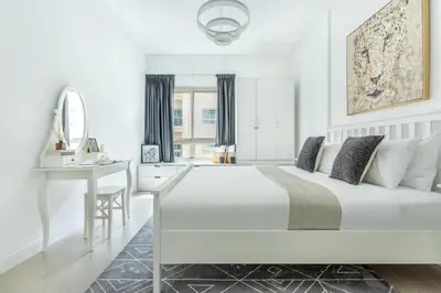a white bedroom with a white bed and a desk at Frank Porter - Al Ghozlan 4 in Dubai