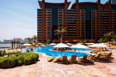 a pool with chairs and umbrellas in front of a hotel at Maison Privee - Splendid Apt on The Palm with Stunning Sea Views in Dubai