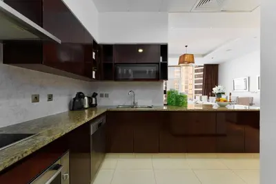 a kitchen with brown cabinets and a counter top at Maison Privee - Splendid Apt on The Palm with Stunning Sea Views in Dubai