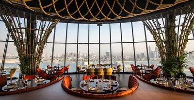 a restaurant with tables and chairs in a room with a large window at LHG PALM JUMEIRAH Tallest RoofTop Pool in Dubai