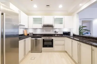a kitchen with white cabinets and a stainless steel refrigerator at Apartment in Golden Mile with access to Fairmont in Dubai