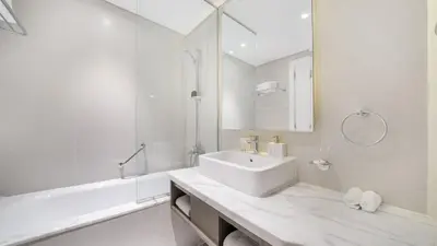 a white bathroom with a sink and a tub at Bright Deluxe Studio canal view - Special offer in Dubai