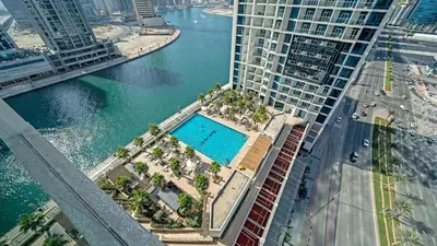 an aerial view of a building with a swimming pool at Bright Deluxe Studio canal view - Special offer in Dubai