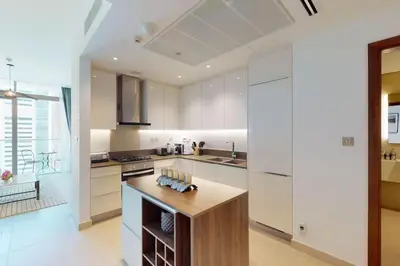 a kitchen with white cabinets and a wooden island at Marina Gate 1, Dubai Marina - Chic One Bedroom in Dubai
