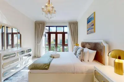 a bedroom with a large bed and a chandelier at Al Tajer, Core C, Souk Al Bahar - Charming Two Bedroom in Dubai