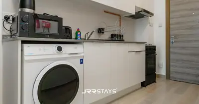 a kitchen with a washing machine and a microwave at Stylish Studio - Panoramic Pool View - JVC in Dubai