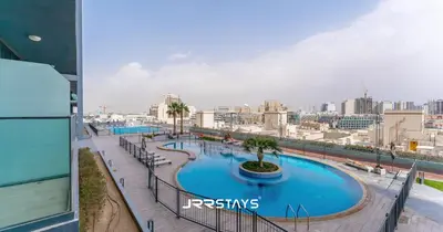 a view of a large swimming pool in a city at Stylish Studio - Panoramic Pool View - JVC in Dubai