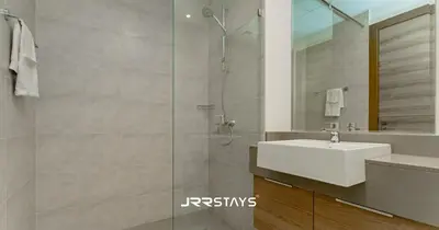 a bathroom with a sink and a glass shower at Stylish Studio - Panoramic Pool View - JVC in Dubai