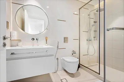 a bathroom with a shower and a toilet and a mirror at Seaside Serenity: 1-BR Apartment with Beach Access in Dubai