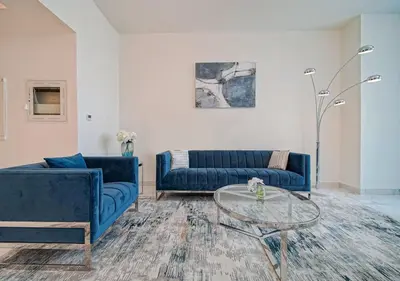 a living room with two blue couches and a glass table at The stylish Meera tower 3606 apartment in Al Habtoor city in Dubai