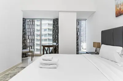 a white bedroom with a large bed and a table at StoneTree - Cayan Tower 2 BR - Best Location in Dubai