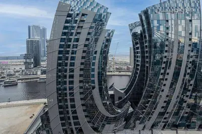 a tall glass building with a view of a city at TURQUOISE - Downtown Dubai 1 BEDROOM APARTMENT Business Bay - CANAL VIEW in Dubai