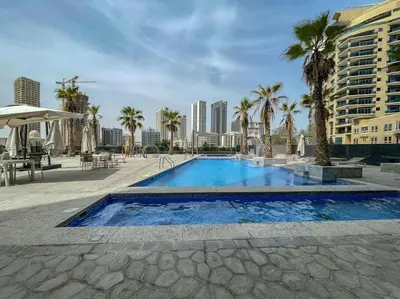 a large swimming pool with palm trees and buildings at Lush Tropical Getaway in Dubai Marina in Dubai