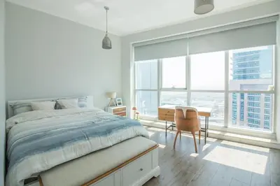 a bedroom with a bed and a desk and windows at Birds Eye 2BR - Torch Tower-L51 - Near Marina Walk in Dubai