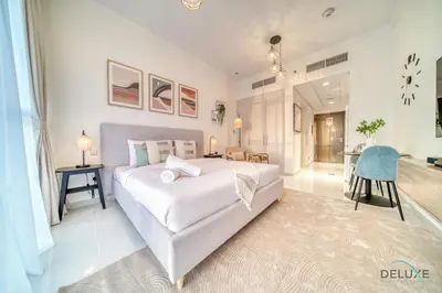 a bedroom with a large white bed and a desk at Picturesque Studio at Carson A DAMAC Hills Dubailand by Deluxe Holiday Homes in Dubai