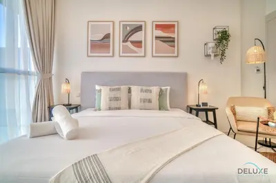 a bedroom with a large white bed with two lamps at Picturesque Studio at Carson A DAMAC Hills Dubailand by Deluxe Holiday Homes in Dubai