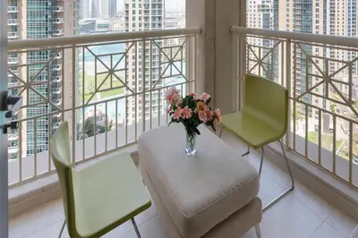 a room with two chairs and a vase of flowers on a balcony at Downtown Dubai, Luxury 2 Bed 2 Bath Apartment - Pool, Gym, AirCon, Parking - Views of The Dubai Fountain & Burj Khalifa in Dubai