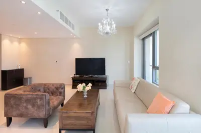 a living room with a couch and a tv at Downtown Dubai, Luxury 2 Bed 2 Bath Apartment - Pool, Gym, AirCon, Parking - Views of The Dubai Fountain & Burj Khalifa in Dubai