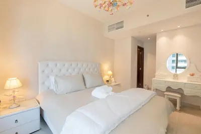 a bedroom with a white bed with a stuffed animal on it at Downtown Dubai, Luxury 2 Bed 2 Bath Apartment - Pool, Gym, AirCon, Parking - Views of The Dubai Fountain & Burj Khalifa in Dubai