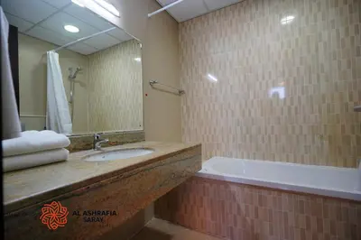 a bathroom with a tub and a sink and a mirror at Alashrafia Saray - Wonderful 1BR in Sports City in Dubai