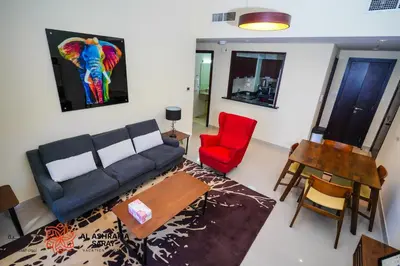 a living room with a couch and a red chair at Alashrafia Saray - Wonderful 1BR in Sports City in Dubai