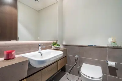 a bathroom with a sink and a toilet and a mirror at GuestReady - Luxury 1BR | Skyline & Canal View in Dubai