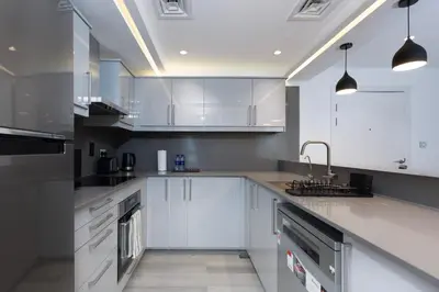 a white kitchen with white cabinets and a sink at Modern Brand New 1BR Holiday Homes at Greens in Dubai