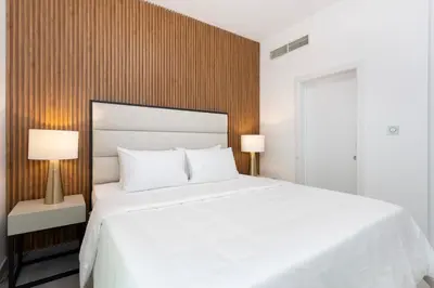a bedroom with a large white bed and two lamps at Modern Brand New 1BR Holiday Homes at Greens in Dubai