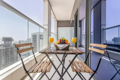 a table with two chairs and a bowl of fruit on a balcony at Damac Towers By Paramount Apartments - The S Holiday Homes in Dubai
