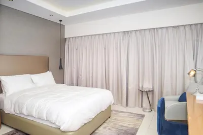 a bedroom with a large white bed and a window at Damac Towers By Paramount Apartments - The S Holiday Homes in Dubai