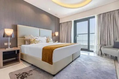 a bedroom with a large white bed and a chair at Damac Towers By Paramount Apartments - The S Holiday Homes in Dubai