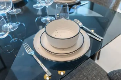a cup and plates on a glass table with a fork at Sophisticated Business Bay Canal View by Suiteable in Dubai