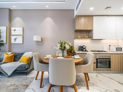 a kitchen and living room with a table and chairs at Charming Condo With Balcony Near Dubai Hills Park in Dubai