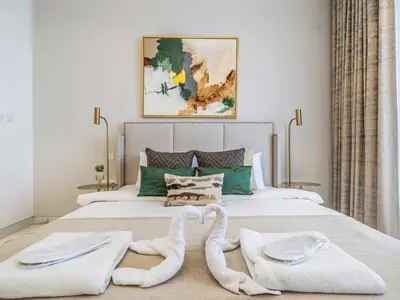 a bedroom with a large bed with towels on it at Charming Condo With Balcony Near Dubai Hills Park in Dubai